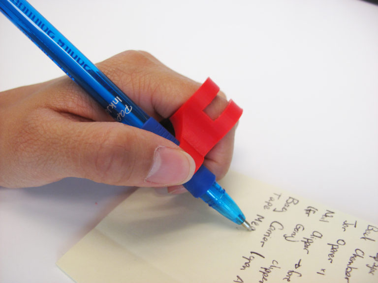 A red finger pencil holder being used to hold a pen.