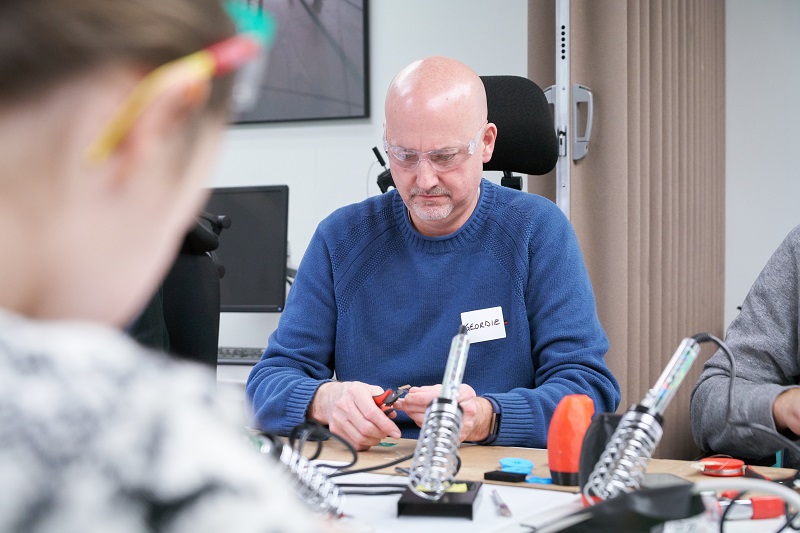 A participant using wire cutters at a build event.