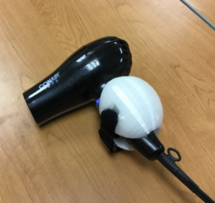 A white 3d printed sphere velcroed to a black hair dryer.