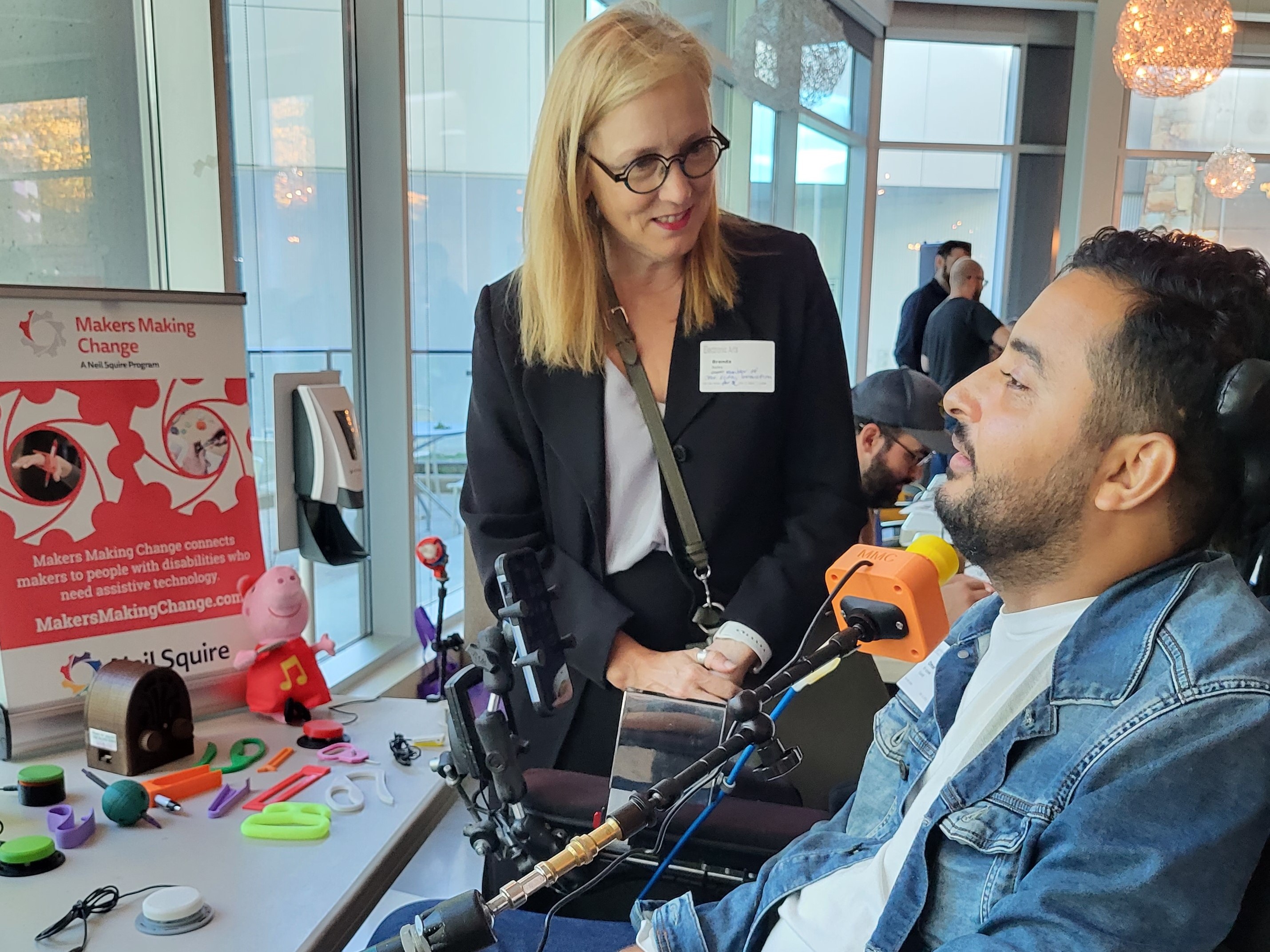 A woman stand and talking to a man in a wheelchair.