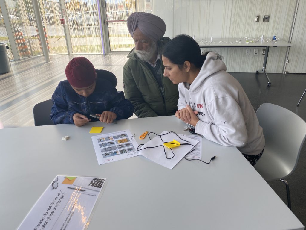 Two adults and a child examining instructions to build an assistive switch.