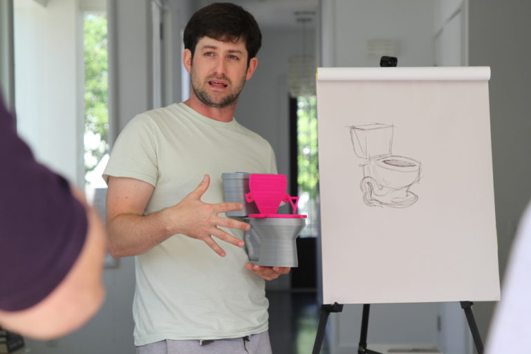 Noam, volunteer for Makers Making Change showing a mockup of the adaptive toilet.