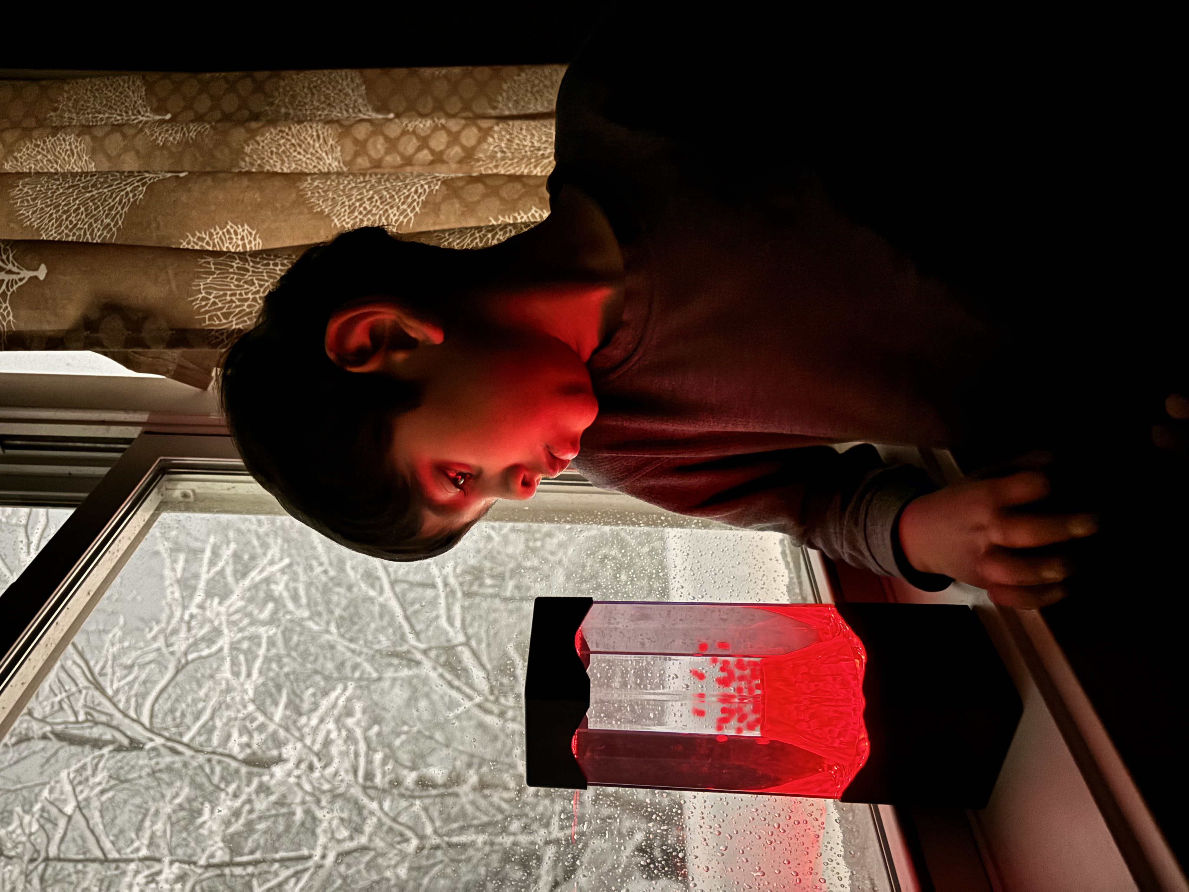A boy watches his red switch adapted Volcano Lamp toy.