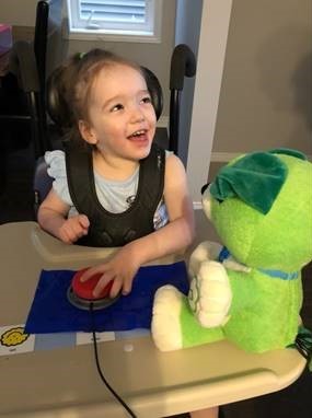 Little girl using an assistive switch to activate a toy.