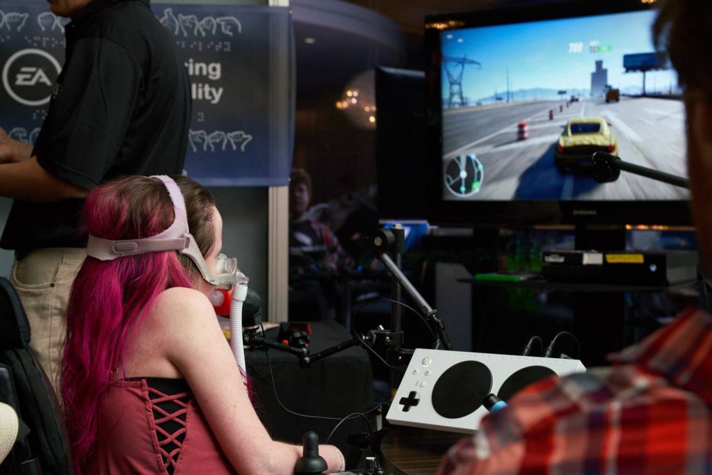 A person with a disability at MMC's EA event testing out an adaptive gaming controller used to control a video game on a TV.